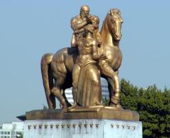 Statue on bridge; man on horseback holding a standing woman.