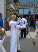 person in white costume with angel-winged staff