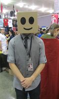 Man wearing cardboard box with smiley face on his head