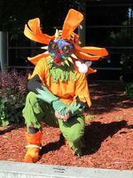 Man in orange and green costume with blue face mask.