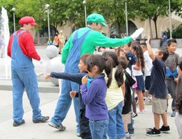 Peopple dressed as the Mario Brothers greeting a group of elementary school children