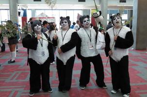 Four men dressed as pandas, holding eucalyptus branches